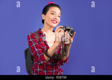 Donna in viaggio. Giovane bella donna asiatica traveler per scattare foto su sfondo blu Foto Stock