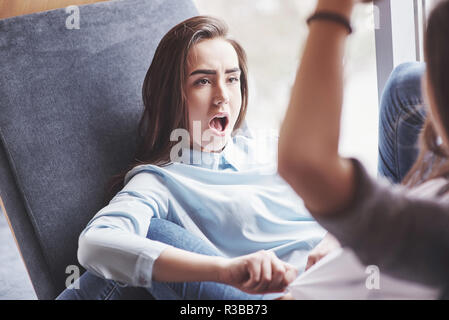 Due figlie gemelle sedersi in una poltrona a tenuta per loro nella zona di ricreazione. Sorelle in posa e divertimento trascorrere del tempo. Sempre unire l amicizia e la gioventù concept Foto Stock