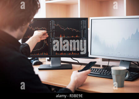 Analizzando i dati. Close-up del giovane imprenditore puntando sui dati presentati nel grafico con la penna mentre si lavora in ufficio creativo Foto Stock