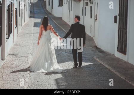 Sposa e lo sposo a piedi lungo la strada in un villaggio mediterraneo Foto Stock