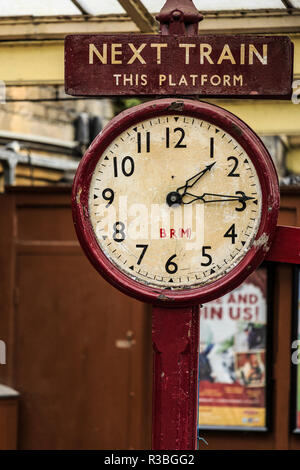 Inghilterra, West Yorkshire. Keighley e Worth Valley Railway, treni a vapore, a 5 miglia a valle che vale la pena di Haworth e Oxenhope. Orologio sulla piattaforma del treno. Foto Stock