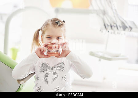 Una bambina lo studio del dentista può contenere un modello della ganascia e pone Foto Stock
