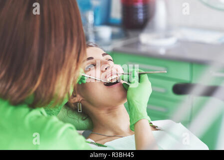 Dentista cura di un paziente di sesso femminile in stomatologia. La prevenzione precoce e igiene orale concept Foto Stock