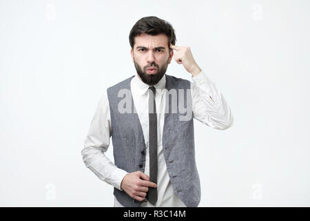 Angry mad giovane uomo gesti con il suo dito contro il tempio chiedendo sei pazzo. Foto Stock