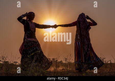 Sagome di due donne zingara ballare una danza tradizionale al tramonto, Pushkar Camel Fair, Pushkar, Rajasthan, India Foto Stock