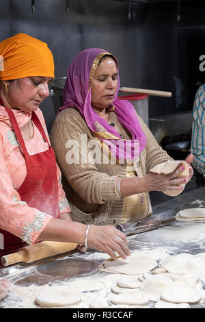 Due donne Sikh rendere roti di langar, una libera lunchroom comunale in un tempio sikh in Richmond Hill, Queens, a New York City. Foto Stock