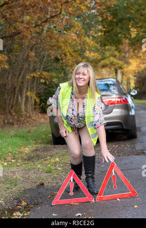 Driver donna messa fuori di sicurezza riflettente triangoli di segnalazione nella parte posteriore di un automobile Foto Stock