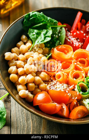 Buddha colorato ciotola con ceci, carote, pomodori, cetrioli, radicchio e peperoni su di un tavolo di legno. Insalata vegetariana. Foto Stock