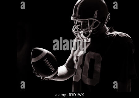 Giocatore di football americano con helmat guardando il pallone da rugby Foto Stock