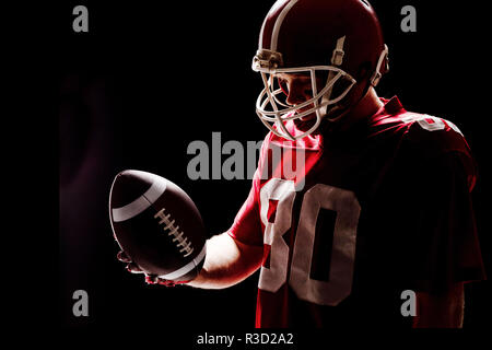 Giocatore di football americano con helmat guardando il pallone da rugby Foto Stock