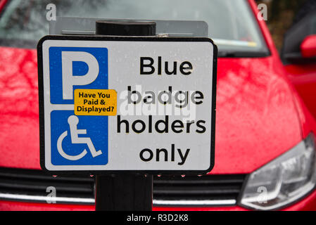 Segno che ricorda i guidatori disabili a pagare per il parcheggio auto. Foto Stock