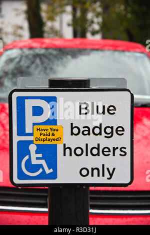 Segno che ricorda i guidatori disabili a pagare per il parcheggio auto. Foto Stock