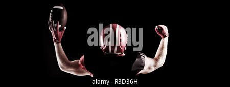 Giocatore di football americano nel casco tenendo palla da rugby Foto Stock
