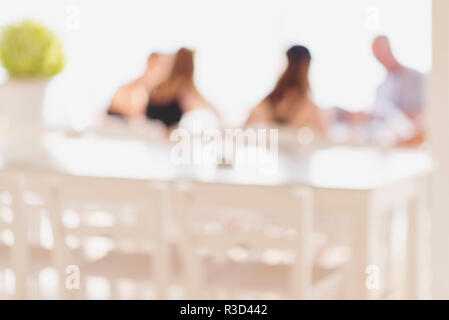 Sfocare lo sfondo della gente seduta in un ristorante, irriconoscibile sagome di un gruppo di amici o familiari Foto Stock