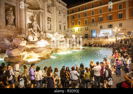 I turisti ed i visitatori si radunano intorno alla famosa fontana di Trevi a notte nel centro di Roma,Lazio,Italia Foto Stock