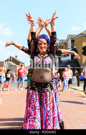 Faversham hop festival. Anaconda gruppo di danza danza del ventre in città con la gente a guardare. Fila di ballerini affacciata con le braccia sollevate sopra le teste. Foto Stock