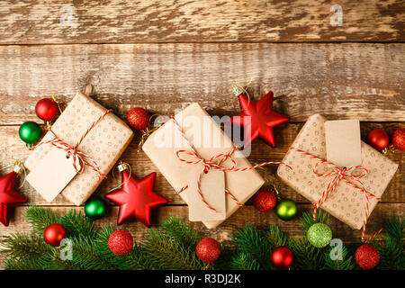 Craft confezione regalo legato con il rosso e bianco corda e decorate con Natale verde e stelle rosse e le sfere su un tavolo di legno, vista dall'alto Foto Stock