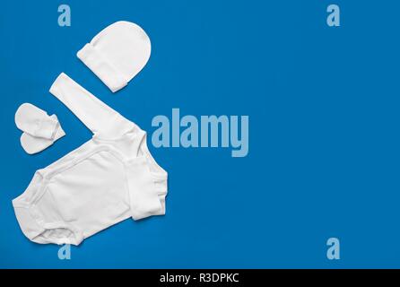 Set di bianco vestiti del bambino su sfondo blu. Foto Stock