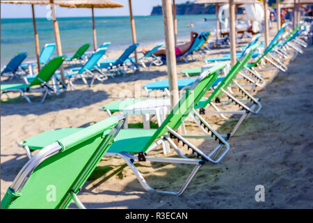 Vista sul pubblico vuoto spiaggia con ombrelloni di paglia, ombrelloni e sedie a sdraio per una vacanza perfetta. Foto Stock