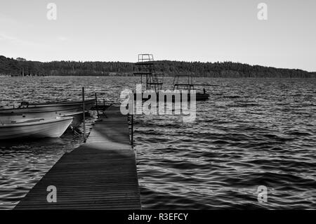 Un molo in legno con un paio di barche che conducono ad un pontile con piattaforme di salto a Teåkersjön, Dalsland, Svezia Foto Stock