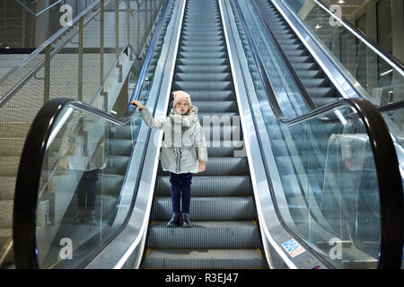 Da sotto tiro della ragazza in piedi sulle scale mobili in terminale. Foto Stock