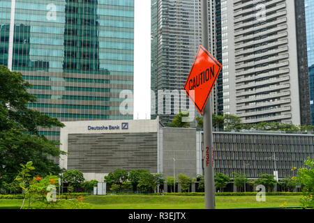 Singapore - 16 Settembre 2017: "Attenzione" strada segno accanto alla Deutsche Bank segno nella costruzione di uffici nel quartiere centrale degli affari di Singapore con n. Foto Stock