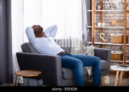 Giovane africano rilassante sul divano di casa Foto Stock
