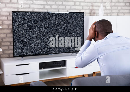 L'uomo africano di toccare la sua testa vicino la televisione mostra nessun segnale Foto Stock