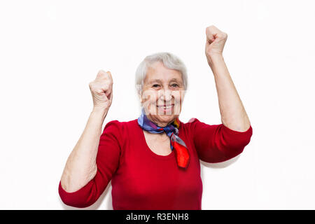 Ritratto di una donna matura facendo un gesto vincitore. Il vecchio donna sorridente con espressioni di sorpresa sul suo volto su sfondo per studio. Le emozioni umane concep Foto Stock