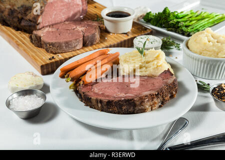 Prime Rib pasto servito su una tabella con gli alimenti che circonda il piatto principale Foto Stock