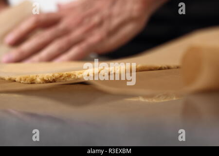 Stendere l'impasto tra due strati di carta da forno Foto Stock