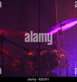 Musica rock dal vivo dello sfondo della foto, il batterista suona sul tamburo di roccia impostato con i cembali in viola le luci dello stadio. Close-up foto, soft focu selettiva Foto Stock