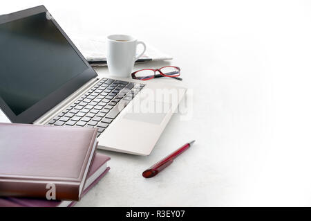 Scrivania da ufficio con computer portatile, calendario , occhiali e una tazza di caffè su una superficie lucida, sfondo si tinge di bianco, spazio copia selezionata, focus, strette dep Foto Stock