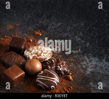 Natale biscotti al cioccolato, panpepato e praline nell'angolo al buio su un sfondo di ardesia con spazio di copia selezionato, focus, profondità di campo ridotta Foto Stock