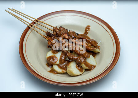 Piatto di riso dolci (lontong) con saté bastoncini da Indonesia Foto Stock