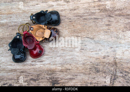 Colorfull portachiavi in pelle a forma di scarpa vecchia su sfondo di legno Foto Stock