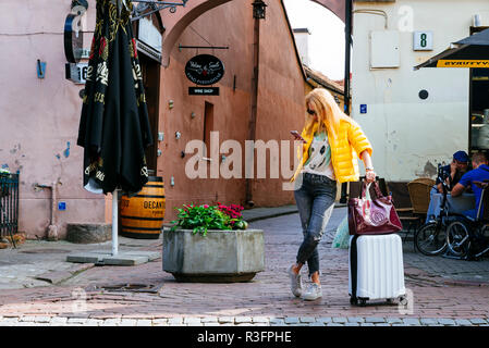 Donna sulla strada che porta un carrello, guardando il telefono. Vilnius, Contea di Vilnius, Lituania, paesi baltici, Europa. Foto Stock