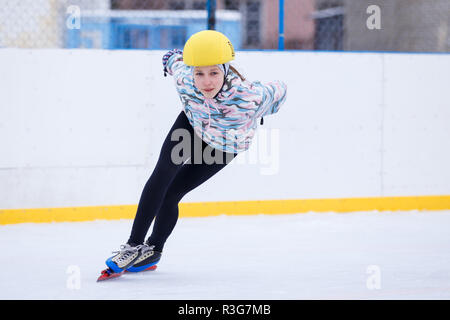 Short track sportive. La pratica del pattinaggio di velocità giovane ragazza sulla formazione rink. Foto Stock