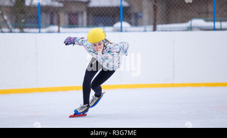 Short track sportive. La pratica del pattinaggio di velocità giovane ragazza sulla formazione rink. Foto Stock