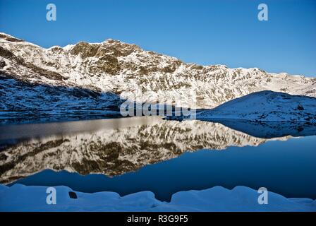 Coperta di neve colline riflessa in un lago di montagna, Mount Snowdon, Parco Nazionale di Snowdonia, Gwynedd, Galles del Nord, Regno Unito Foto Stock