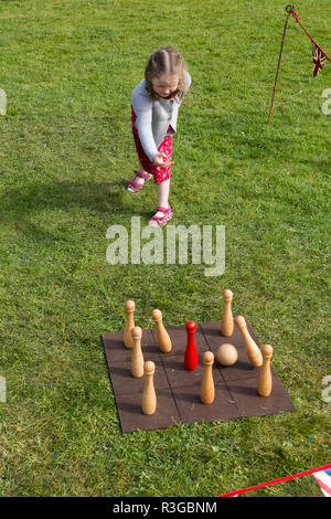 Un bambino di sei anni ragazza che gioca con un vecchio stile classico tradizionale serie di birilli su un consiglio di amministrazione che richiedono il lancio di una palla da parte dei giocatori. Regno Unito (98) Foto Stock