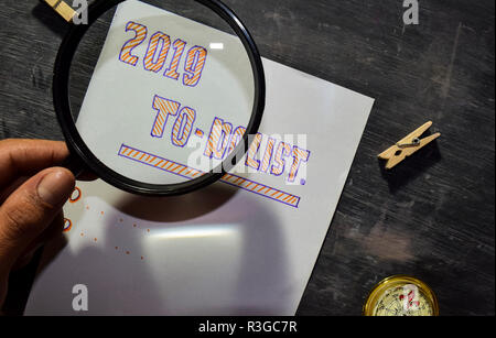 2019a - Elenco delle attività il testo scritto a mano su carta con il marcatore, bussola e utilizzare la lente di ingrandimento sulla lavagna sfondo. Ispirazione, istruzione e cel Foto Stock