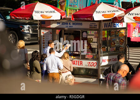 NEW YORK CITY - Stati Uniti d'America - 02 novembre 2017. Alcuni turisti acquistano cani a caldo da un chiosco in Times Square. Foto Stock