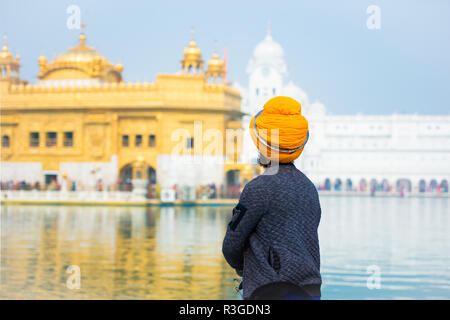 Un religioso sikh è ammirando il maestoso tempio d'oro di Amritsar nello stato del Punjab, India. Foto Stock