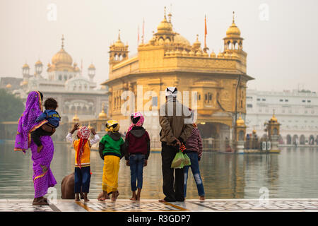 Una famiglia indiana è di ammirare il maestoso tempio d'oro di Amritsar nello stato del Punjab, India. Foto Stock