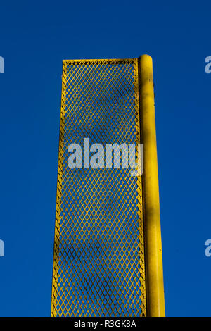 Giallo fallo polo ricreativo sul campo da baseball è incorniciato contro un profondo cielo blu. Foto Stock
