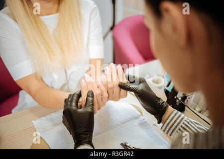 Per la ricostruzione professionale delle unghie artista in nero Guanti rendendo manicure naturale Foto Stock