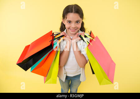 Esperto di moda. Bambino graziosi negozi expert aiuta a portare pacchetti durante lo shopping. Little Shop esperto. Shopping ragazza ama fare shopping. Ragazza di capretto felice fa Foto Stock