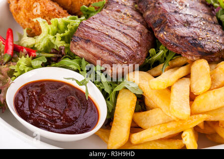 Enorme barbecue piastra con misto di carne e bistecche su lattuga Foto Stock
