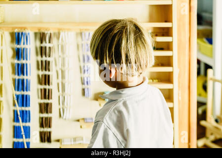 Le mani di un bambino la manipolazione di materiali didattici per imparare a contare in una classe Montessori. Foto Stock